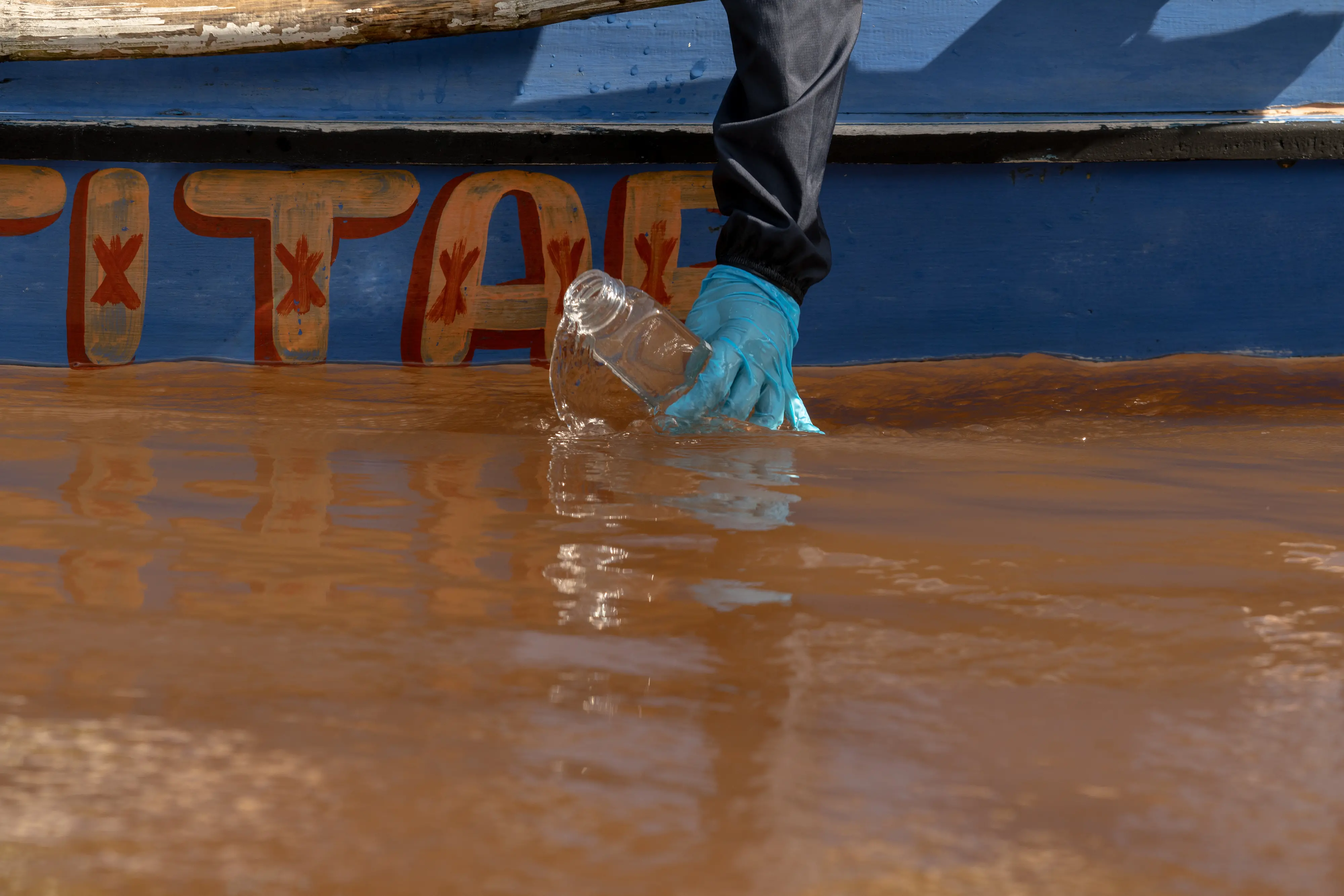 A reporter takes a water sample