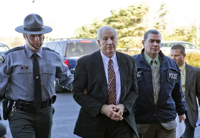 Jerry Sandusky is escorted in handcuffs.