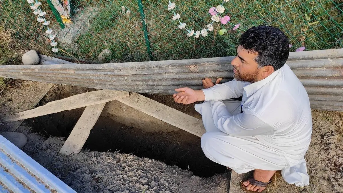 a father prays at an empty grave