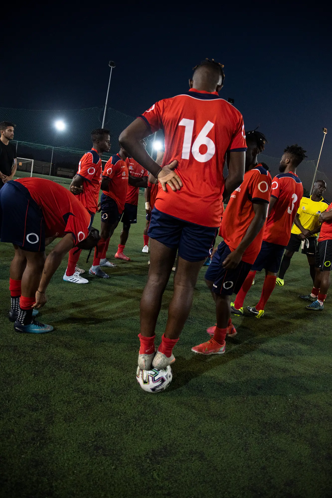 soccer player stands on soccer ball amid teammates