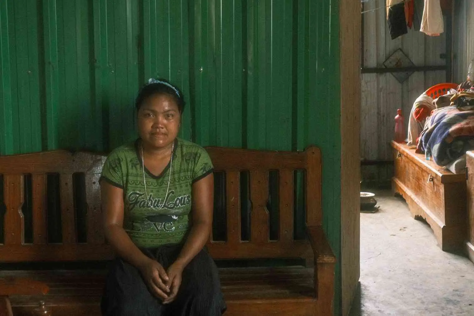 A woman wearing a green shirt sits on an indoor bench.