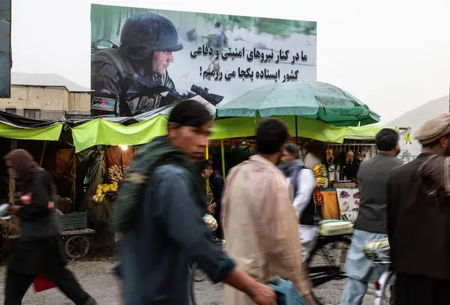 a man walks through a crowded market in Kabul