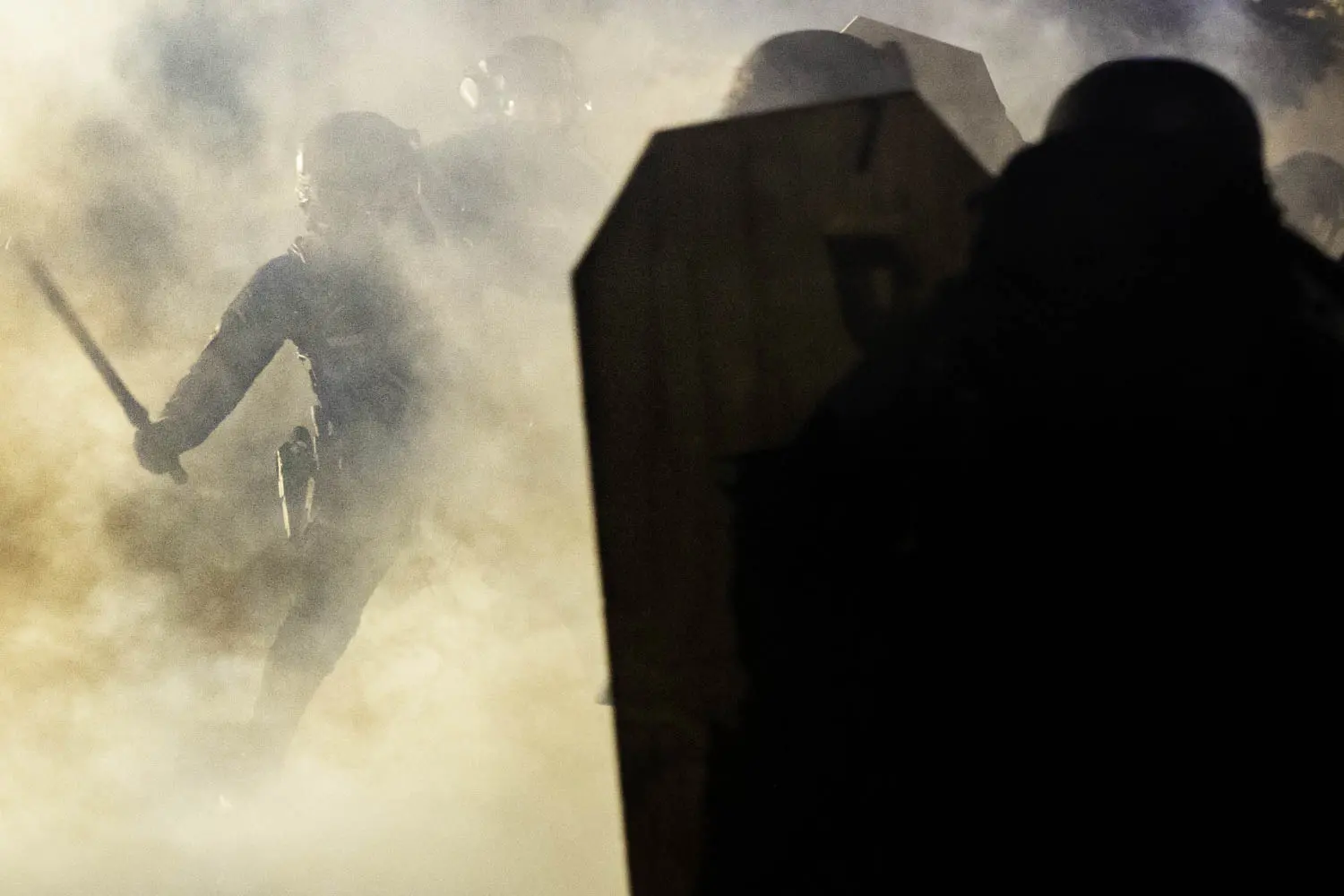 A Portland Police officer wields a billy club against a protester amidst a cloud of teargas<br />
outside of the North precinct in Portland, Oregon.