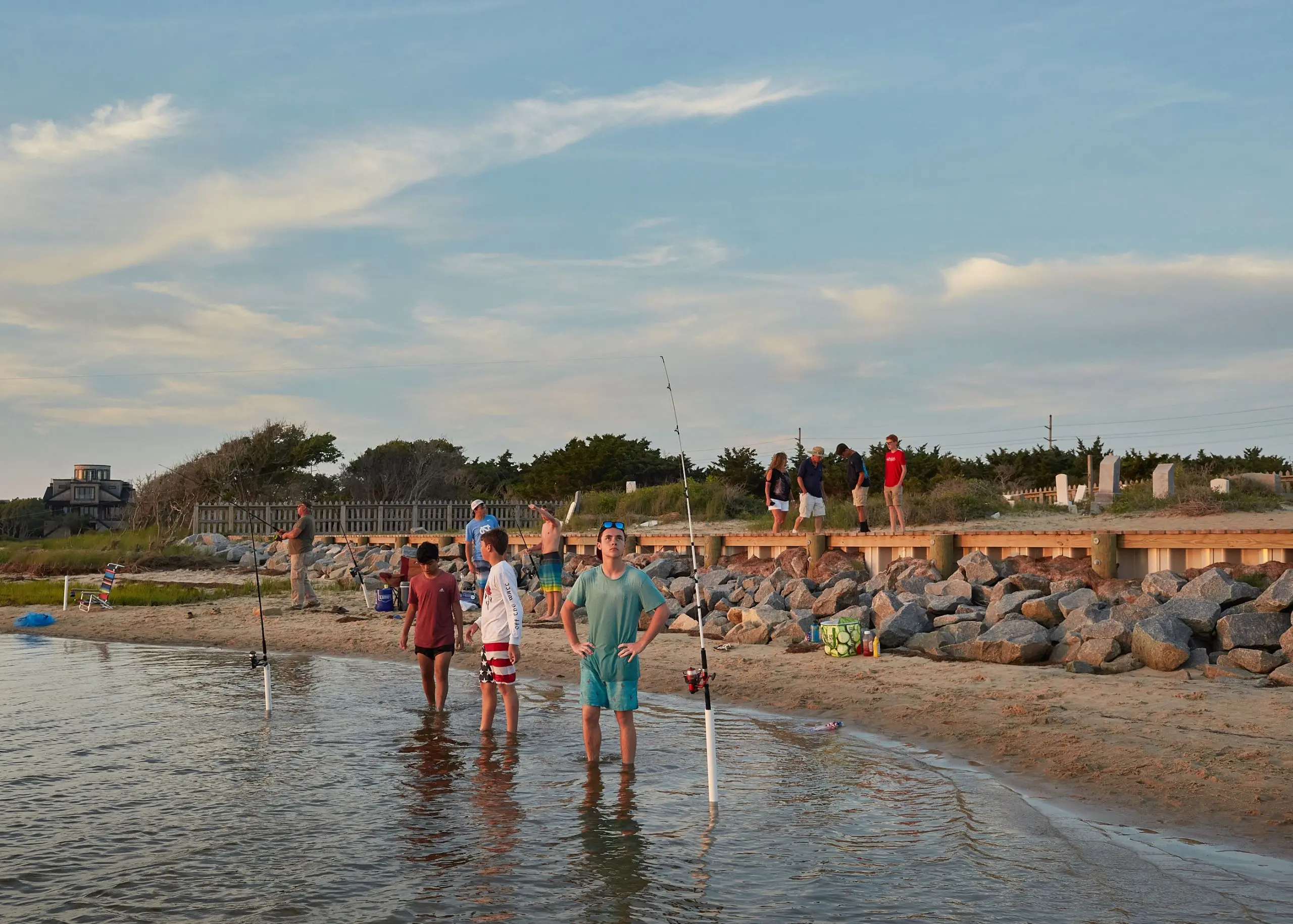 People fish in front of the gravestones