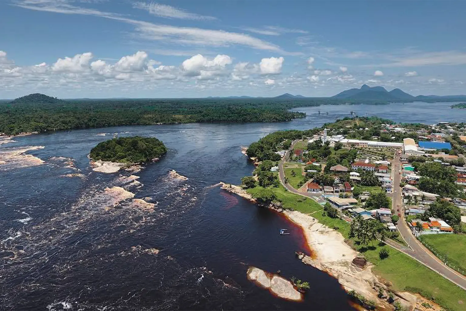 Overhead photo of the Rio Negro and the town of Sao Gabriel da Cachoeira with mountains in the distance.
