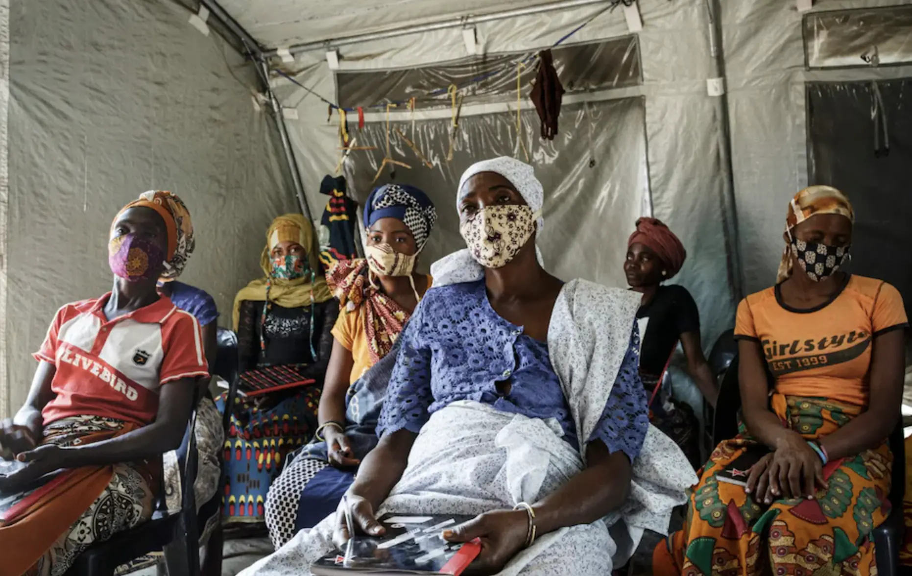 Women sit masked taking lessons in IDP camp