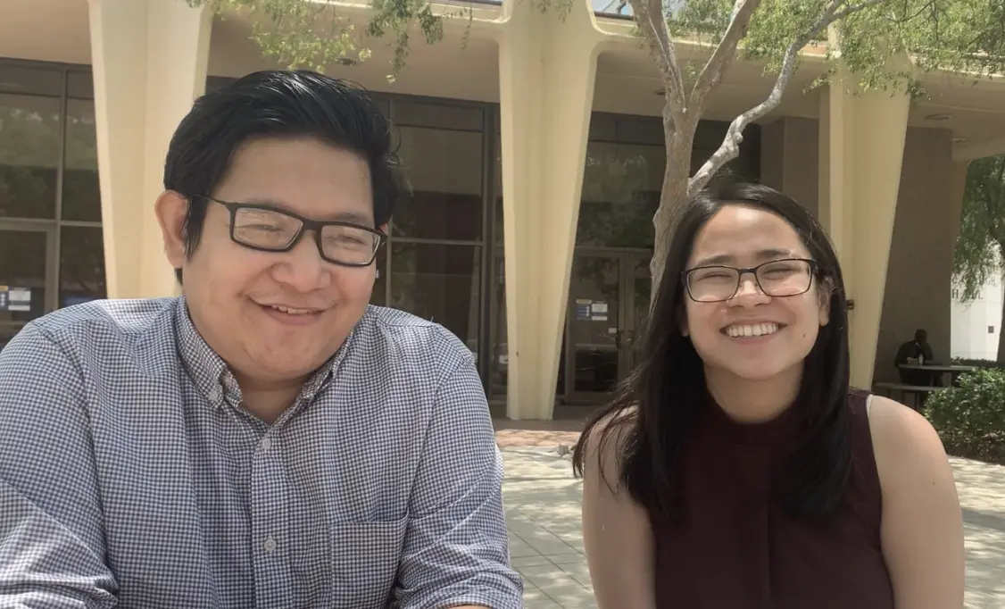 a man and woman sit next to each other in front of a building