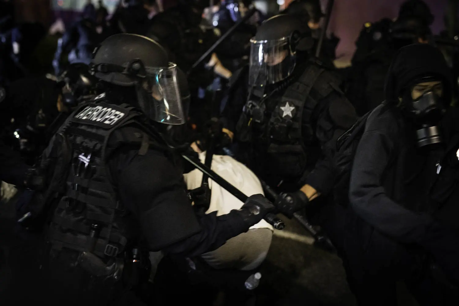 Oregon State Troopers use their clubs on a group of protesters in Portland, Oregon.