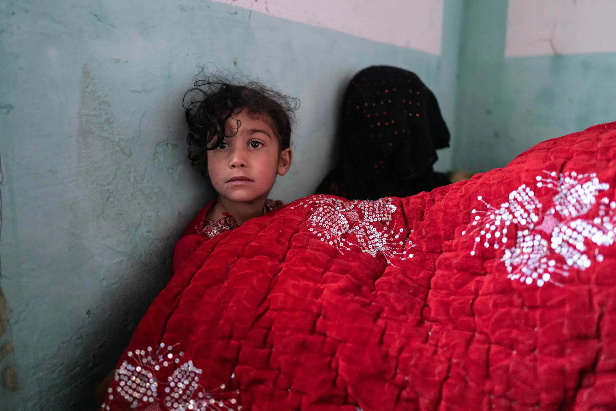 A young girl sits below blankets