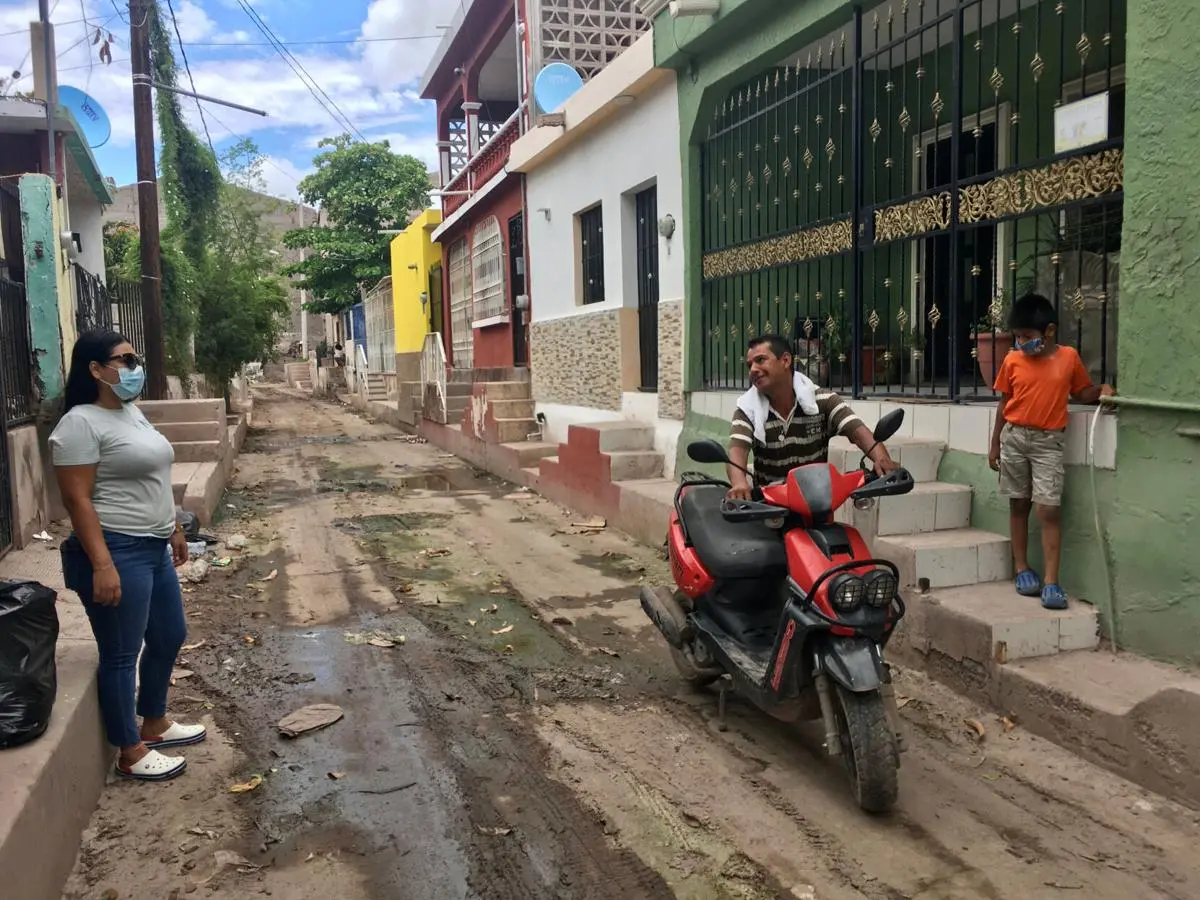 A man on a scooter talks to masked woman in street