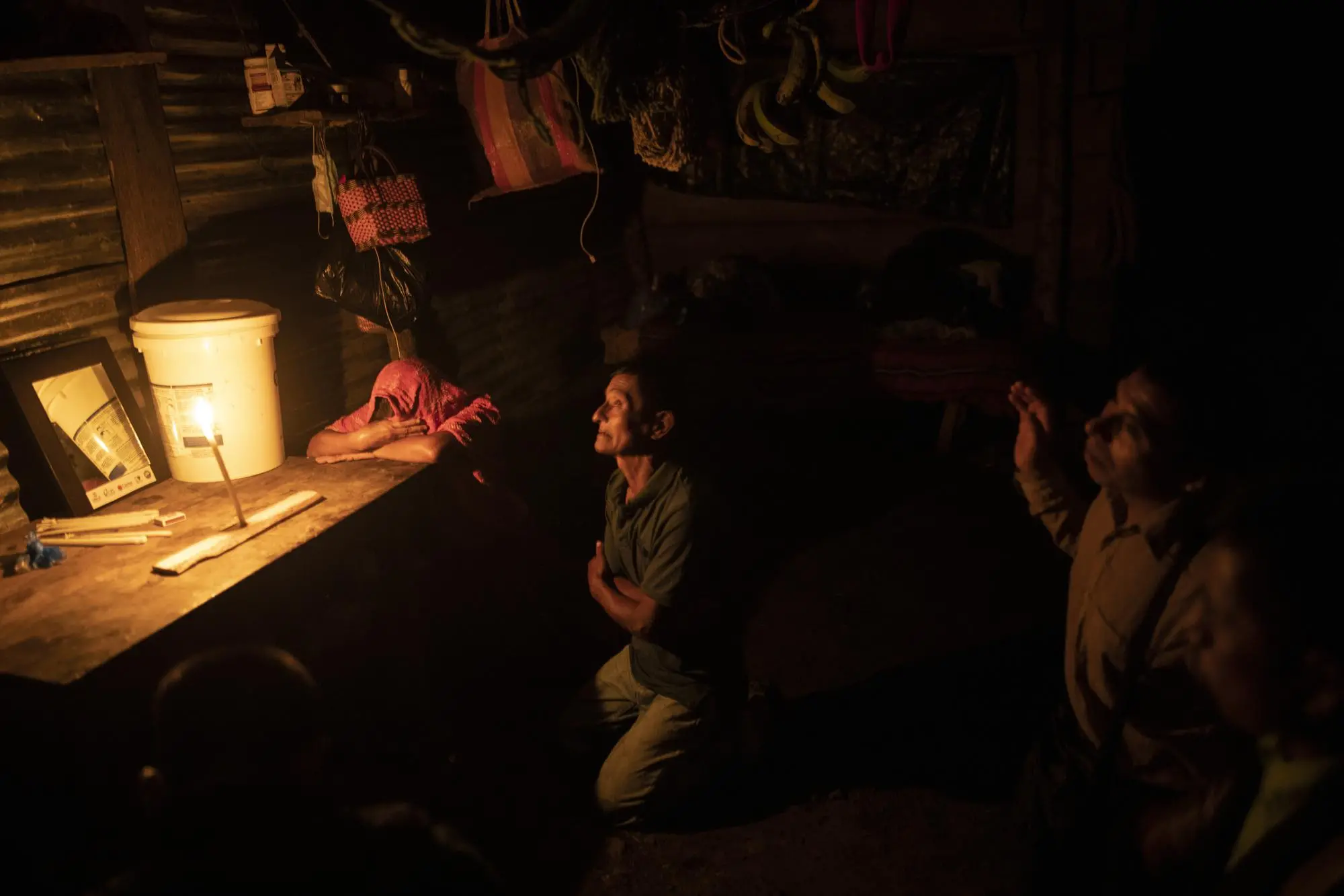 A group of Guatemalans pray in front of a small candle