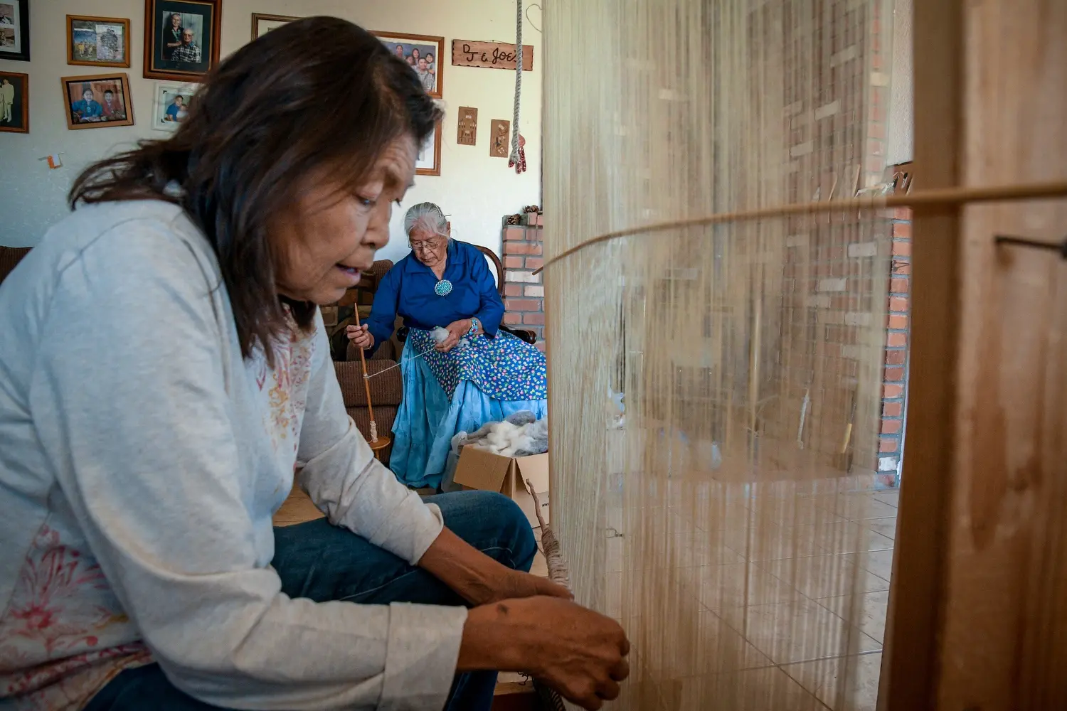 Augusta Gillwood and her mother, Cecilia Joe, prepare sheep’s wool and a loom to weave a rug at their home near Tuba City. Image by Mary F. Calvert. United States, 2020.