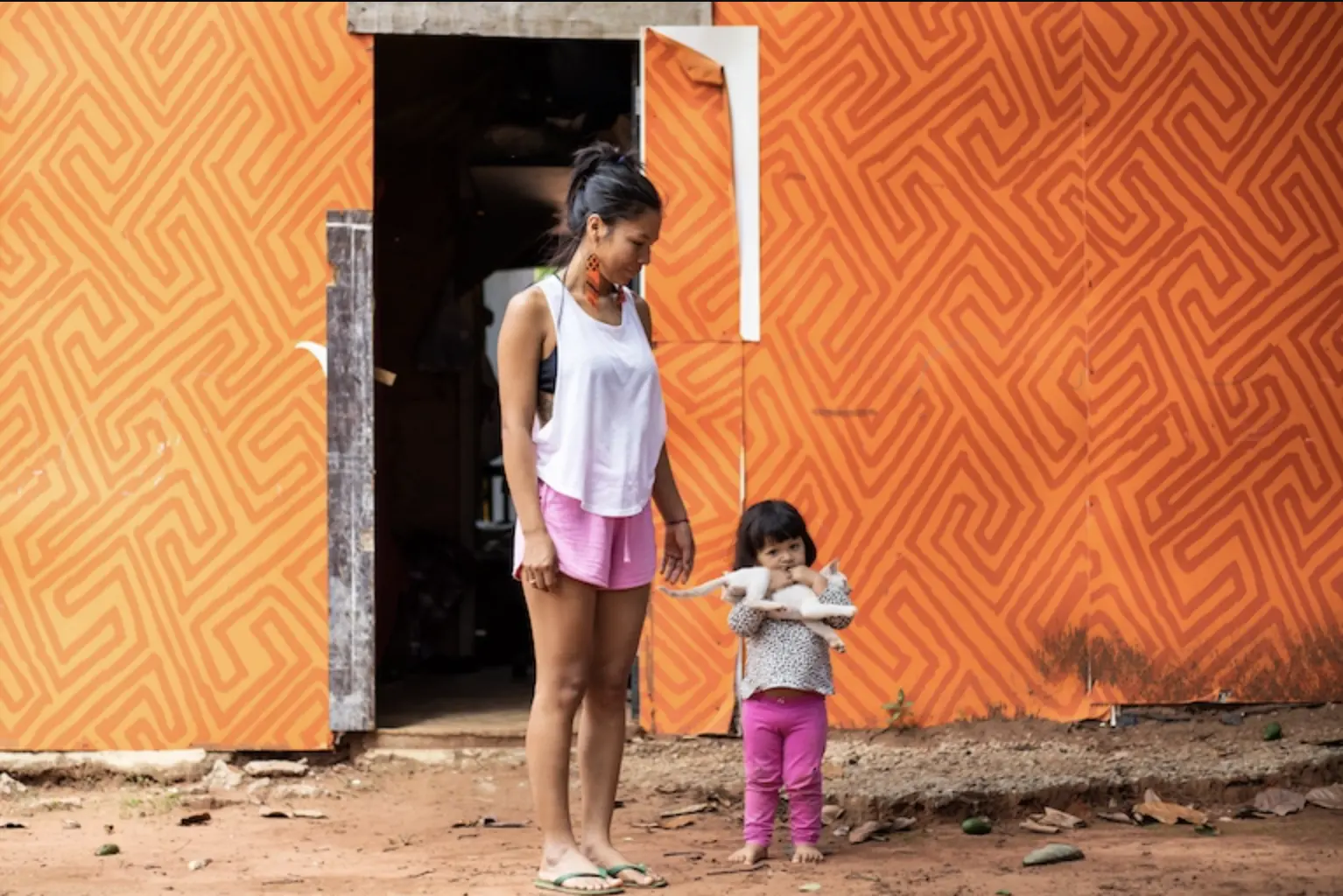 Shirlene Tukano stands next to a young child, who is holding a cat.