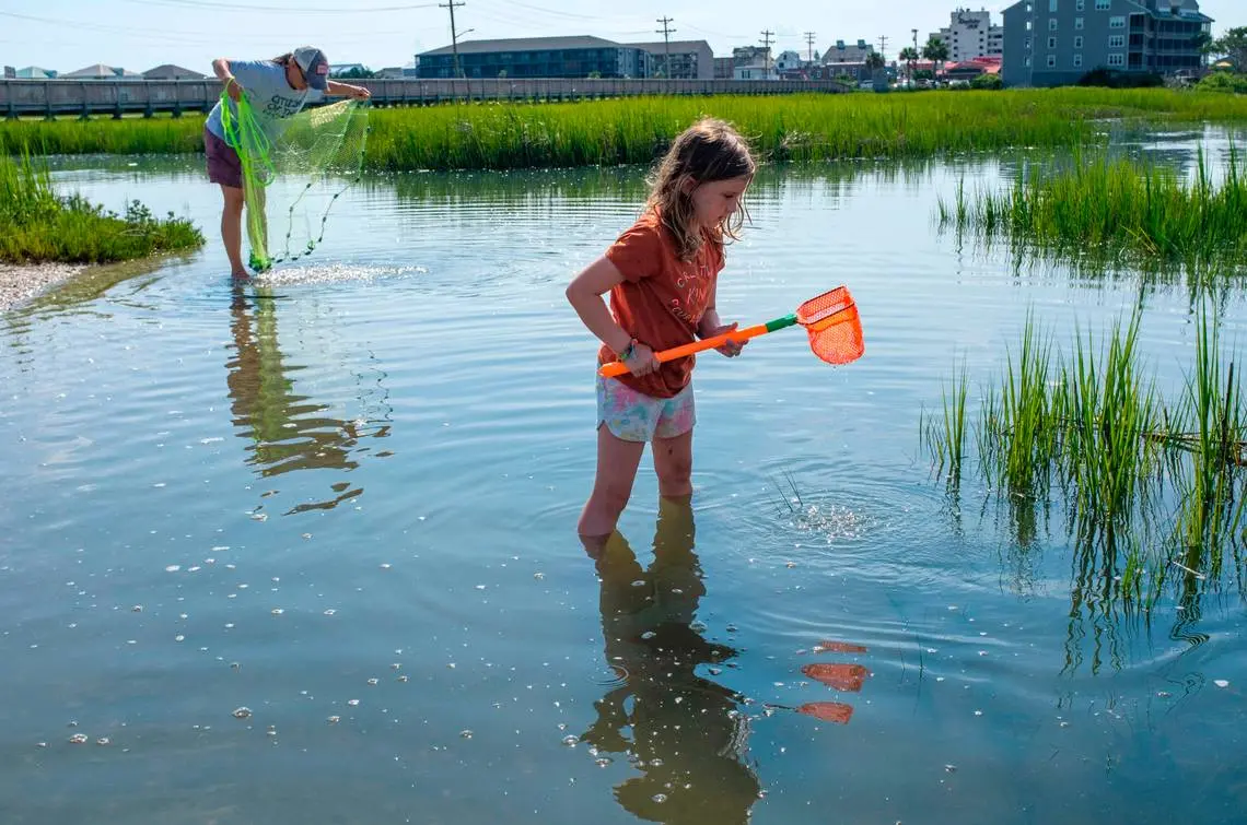 Young girl fishes during high tide in the marsh