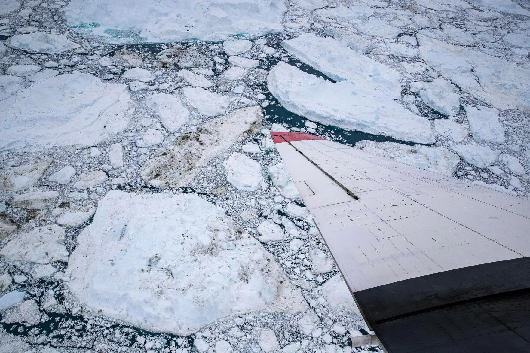 A plane flies over a glacier