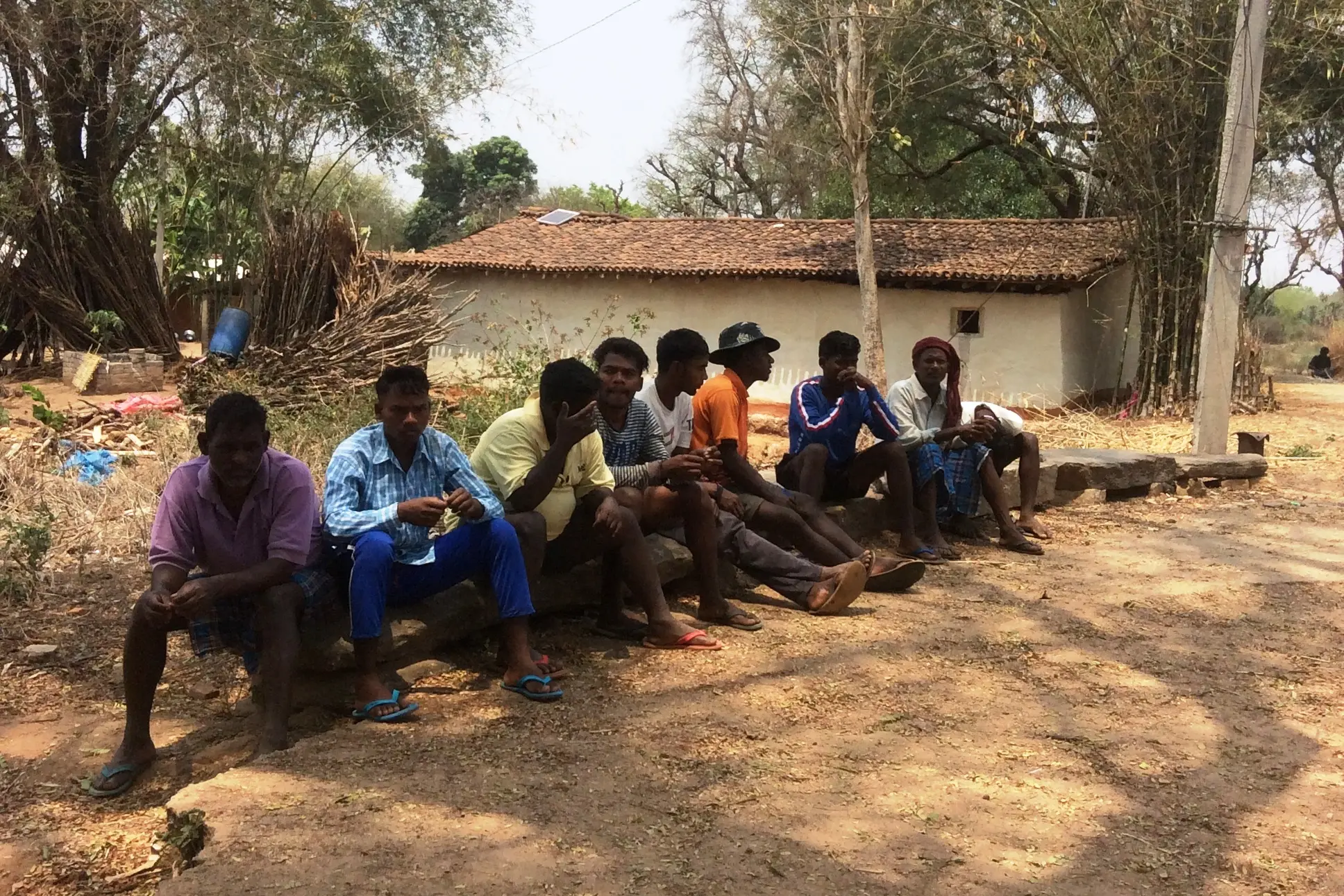 Men sit together in the village on benches.
