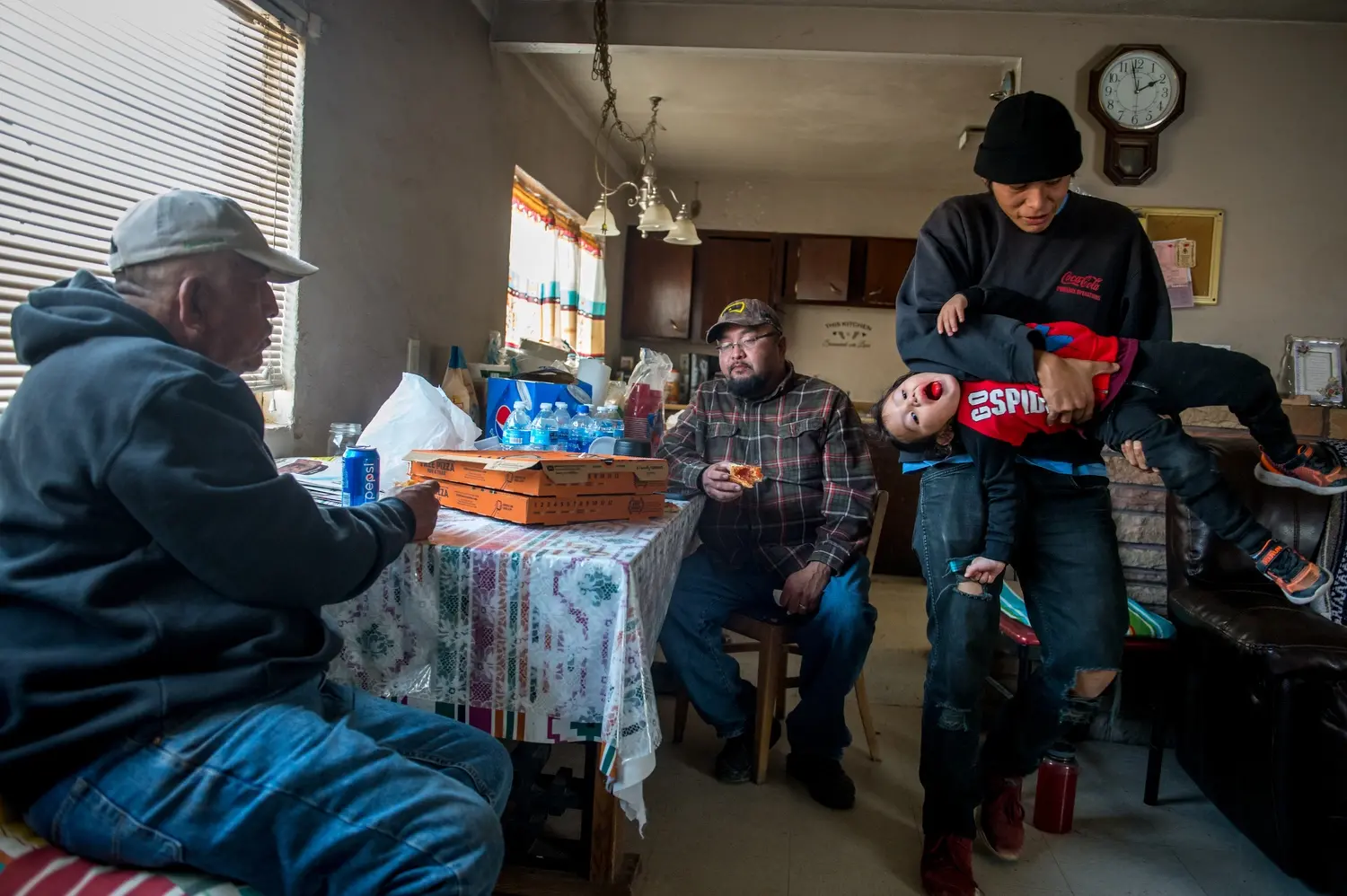 Leroy Canyon, Brandon Canyon, Eagle Spencer and Brandon’s son, Bryce Canyon, are pictured eating pizza at the family home in Tuba City after bringing water to their family’s cattle in Coalmine, Ariz. Image by Mary F. Calvert. United States, 2020.