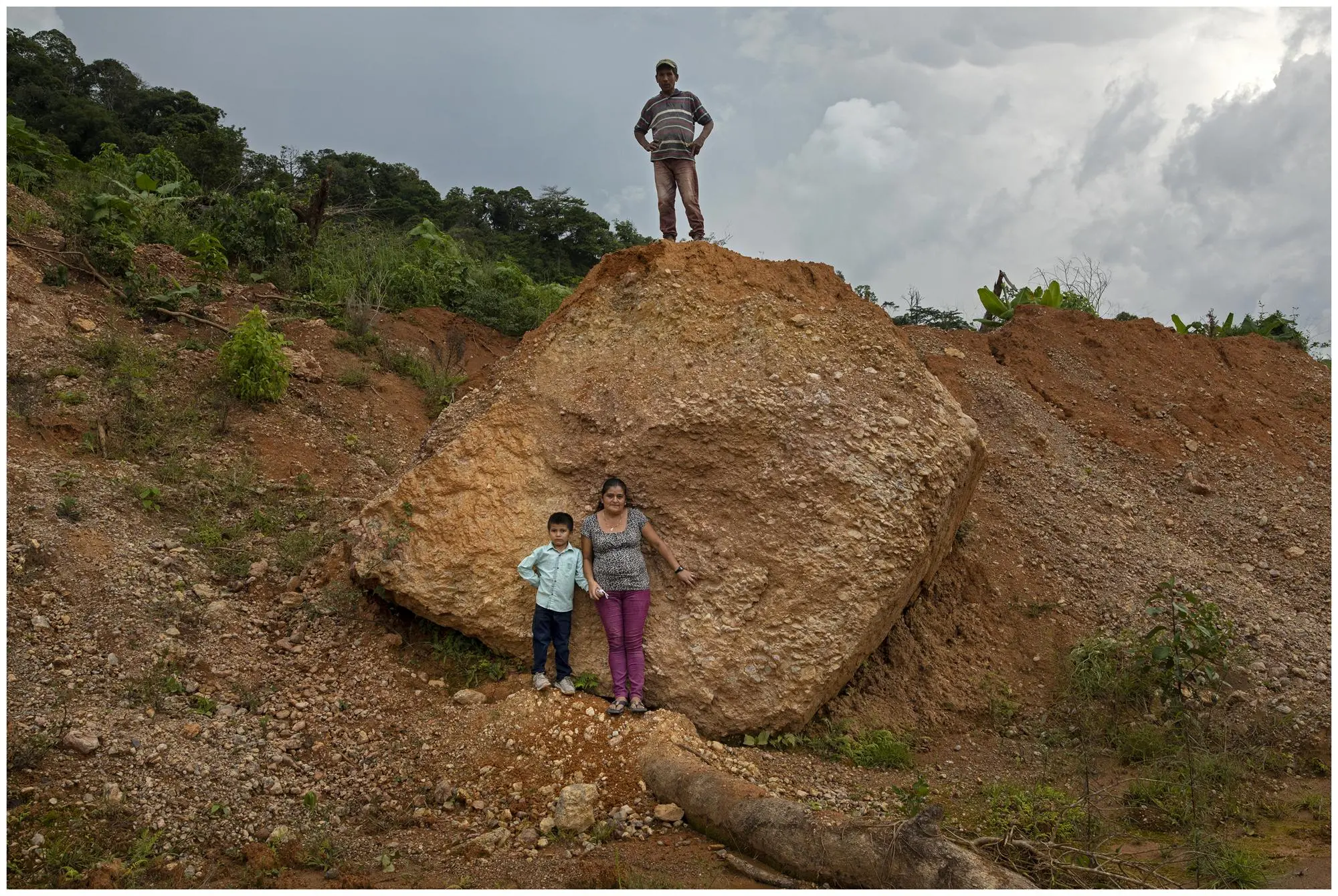 A family stands in front of rock where home was destroyed