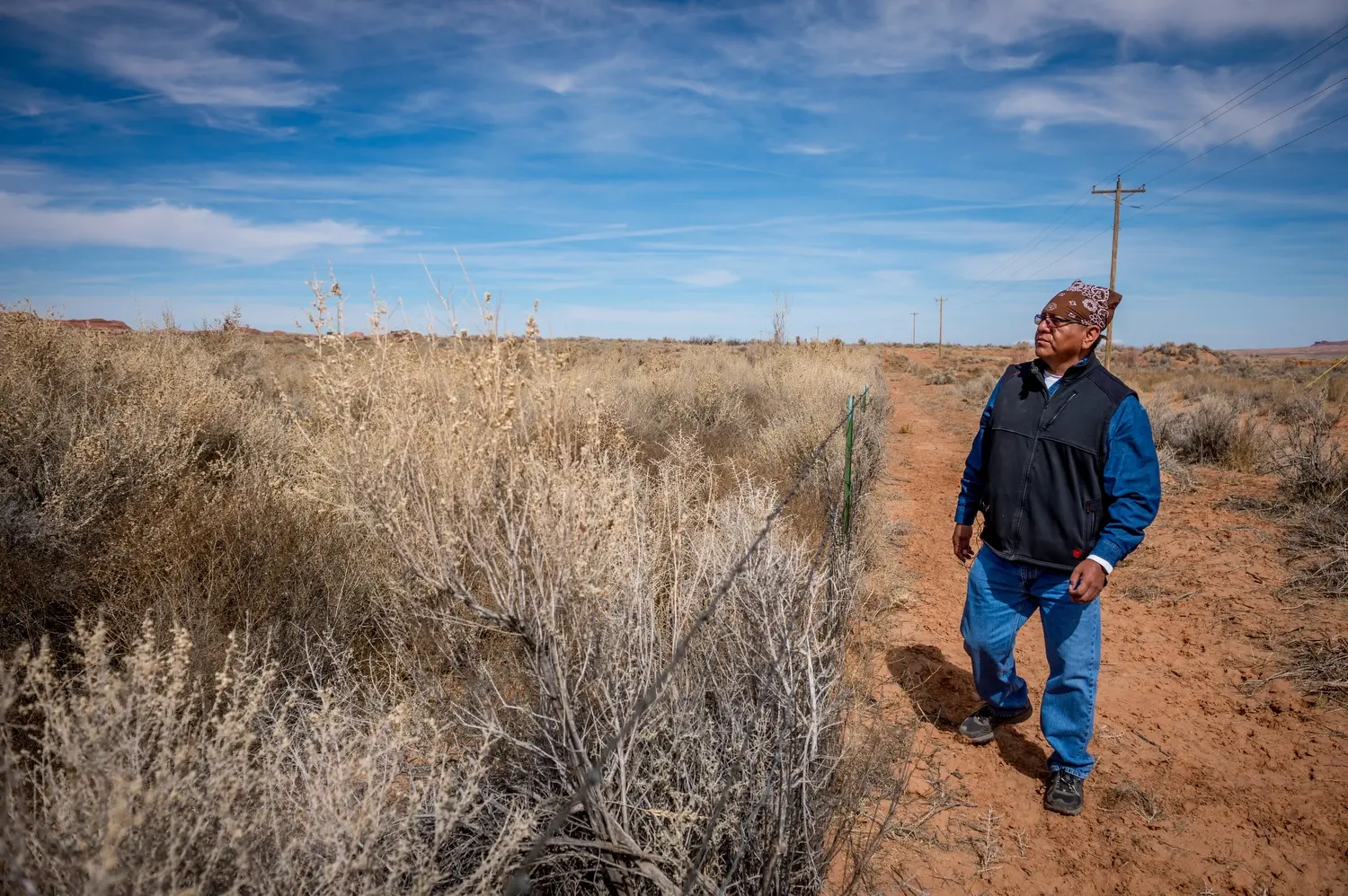 Dariel Yazzie walks along the fence around the covered-uranium tailings pile near his family’s house. Image by Mary F. Calvert. United States, 2020.