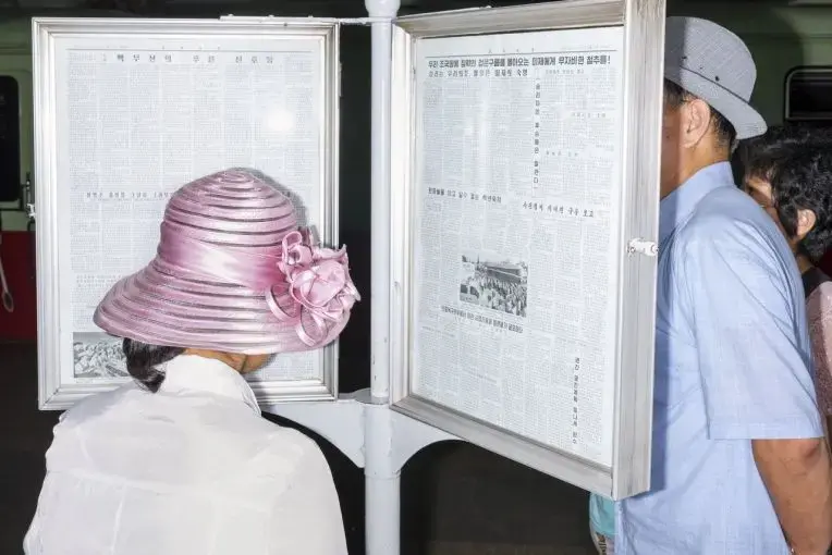 Commuters reading the official newspaper on a Pyongyang Metro platform. Commuters reading the official newspaper on a Pyongyang Metro platform.
