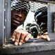 Detainees from West Africa peer out of their overcrowded cell in the Nasr detention center in Zawiya, where migrants intercepted by the coast guard are warehoused indefinitely. Image by Peter Tinti. Libya, 2017.