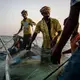 Shafai (center) and his sons, Isa (left) and Musa (right), pull in their nets, hoping they'll be filled with fish. Image by Alex Potter. Yemen, 2018.