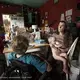 Allison, a mother of eight, breastfeeds her youngest daughter at the kitchen table in their two-bedroom cabin on a commune in the redwood forest. Past a gate marked ‘Private Property — Keep Out,’ the Murphy family live with no plumbing, indoor bathroom, heat, or central air. Image by Rachel Bujalski. United States.