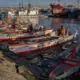 A few men sitting on their boats, waiting for passengers on a Wednesday afternoon at the Navotas Fish Port Complex. Their passengers are typically men who work in cargo ships and fishing boats in Manila Bay. Image by Micah Castelo. Philippines, 2019.