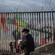 A musician visits the border wall at Playas de Tijuana at sunset Dec. 1. The artwork on the border wall is temporary and changes frequently. Image by Amanda Cowan. Mexico, 2019.