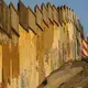 A man sits by the border wall at Friendship Park as the sun sets over Playas de Tijuana on Dec. 1. Image by Amanda Cowan. Mexico, 2019.