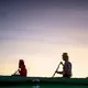 Duane Hanson and Sally Kwan are reflected in the water of Whipple Pond during a sunset paddle in the Unorganized Territories in the north woods of Maine near T5 R7 on May 27, 2019. Image by Michael G. Seamans. United States, 2019.