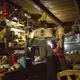 Duane Hanson and Sally Kwan prepare dinner by headlamp at their home on Whipple Pond in T5 R7 in the Unorganized Territories of Maine on May 26, 2019. The homestead is equipped with one solar panel that powers a satellite phone charger and one light bulb over the kitchen table. Image by Michael G. Seamans. United States, 2019.