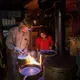 Duane Hanson and Sally Kwan prepare dinner at their home on Whipple Pond in T5 R7 in the Unorganized Territories of Maine on May 26, 2019. Using an antique wood stove, they cook dinner and heat the cabin. Image by Michael G. Seamans. United States, 2019.