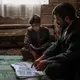 Yahya reads Salah's English workbook with him, pronouncing difficult words together. Image by Alex Potter. Yemen, 2018.