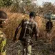 Two suspected poachers arrested deep in the Chinko bush are escorted to a helicopter, which will fly back to base. There, the men will be questioned in a holding cell. Image by Jack Losh. Central African Republic, 2018.