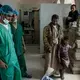 Rasheed (center) talks with doctors about his son's medical care. He and his son traveled eight hours to visit the facility. Image by Alex Potter. Yemen, 2018.