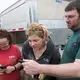 Truck driver and farmer Dan Richards, right, shares photos of his farm with Brandi, left, and Emily Harris. Image by Mark Hoffman. United States, 2019.