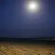 The moon shines on the beach, July 14, 2019, in Obock, Djibouti, where smugglers take Ethiopian migrants by boat to Yemen. The trek through Djibouti ends on a long, virtually uninhabited coast outside the town of Obock, the shore closest to Yemen. Here migrants would stay, sometimes for several days, and wait for their turn on the boats that every night cross the narrow Bab el-Mandeb strait to Yemen. Image by AP Photo / Nariman El-Mofty. Djibouti, 2019.