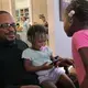 Cecil Burton rocks his granddaughters Chasity Shufford, 1, and Katelyn Ellis, 6, during a family gathering while their mother, Keisha, cooks fried chicken in the kitchen. Burton, 54, said child support once garnished so much of his paycheck he didn't have enough to live on. His coworkers took up a collection for him. Image by Karl Merton Ferron / Baltimore Sun. United States, 2019.<br />
