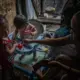 To earn money, Jasmine Durana’s sister, Joanna, and her mother, Vicky, take care of children during the day in their house. Image by James Whitlow Delano. Philippines, 2018. 