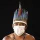 Eleomar da Silva, 44, of the Sateré Mawé indigenous ethnic group, poses for a portrait wearing the traditional dress of his tribe and a face mask amid the spread of the new coronavirus in the Gaviao community near Manaus, Brazil, Friday, May 29, 2020. Image by Felipe Dana / AP Photo. Brazil, 2020.