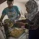 Noor Al Talaa, 22, and her husband, Yousuf Arsan, 27, prepare lunch at home with baby Rahaf, almost 6 months, at an apartment in Sidros, outside of Thessaloniki, Greece. Image by Lynsey Addario. Greece, 2017.