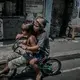 Young boys ride past a tombstone engraving shop on in Navotas. Image by James Whitlow Delano. Philippines, 2018.