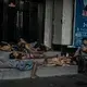 Street children and a man with cerebral palsy shelter in the doorway of a hostess bar in Malate, Manila, a known area for sex tourists from South Korea and Japan. In Manila, thousands of people sleep outside in doorways, under awnings on the sidewalks and on sea walls every night of the year. Image by James Whitlow Delano. Philippines, 2018. 