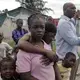 Cami Etienne, far right, talks about the situation in Haiti in the company of some of the children who live in a makeshift camp located off a dirt road in the interior of Delmas. Image by Jose A. Iglesias. Haiti, 2019.