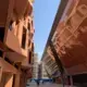 Masdar City’s streets are narrow and lined with buildings that promote cool street temperatures. The terracotta residential building on the left has screens which shade the rooms inside. The incubator building to the right slopes outward to further shade the streets below. Construction continues in the background. Image by Anna Gleason. United Arab Emirates, 2019.