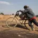 A miner pushes a bicycle without pedals piled with sacks of cobalt from a mining pit to the depot inside the Kasulo mine. Image by Sebastian Meyer. Democratic Republic of Congo, 2018.