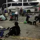 Chartered buses are parked behind a group of migrants at an immigration checkpoint in Nuevo Laredo. The buses are scheduled to transport the group to the state of Chiapas, near the Guatemalan border. Aug. 7, 2019. Image by Daniel Méndez. Mexico, 2019.