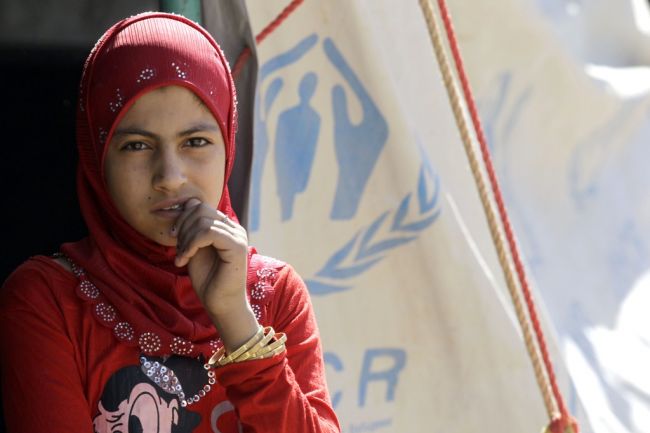 A Syrian refugee girl, who fled the violence in her country, stands outside a refugee camp close to the Syrian border, on July 17, 2012. According to the UNHCR, the number of refugees has tripled since April, reaching 110,000 at camps in Turkey, Lebanon, Iraq and Jordan. (Khalil Mazraawi/AFP/Getty Images) Media file: syria_refugee_crisis_tide-1.jpg