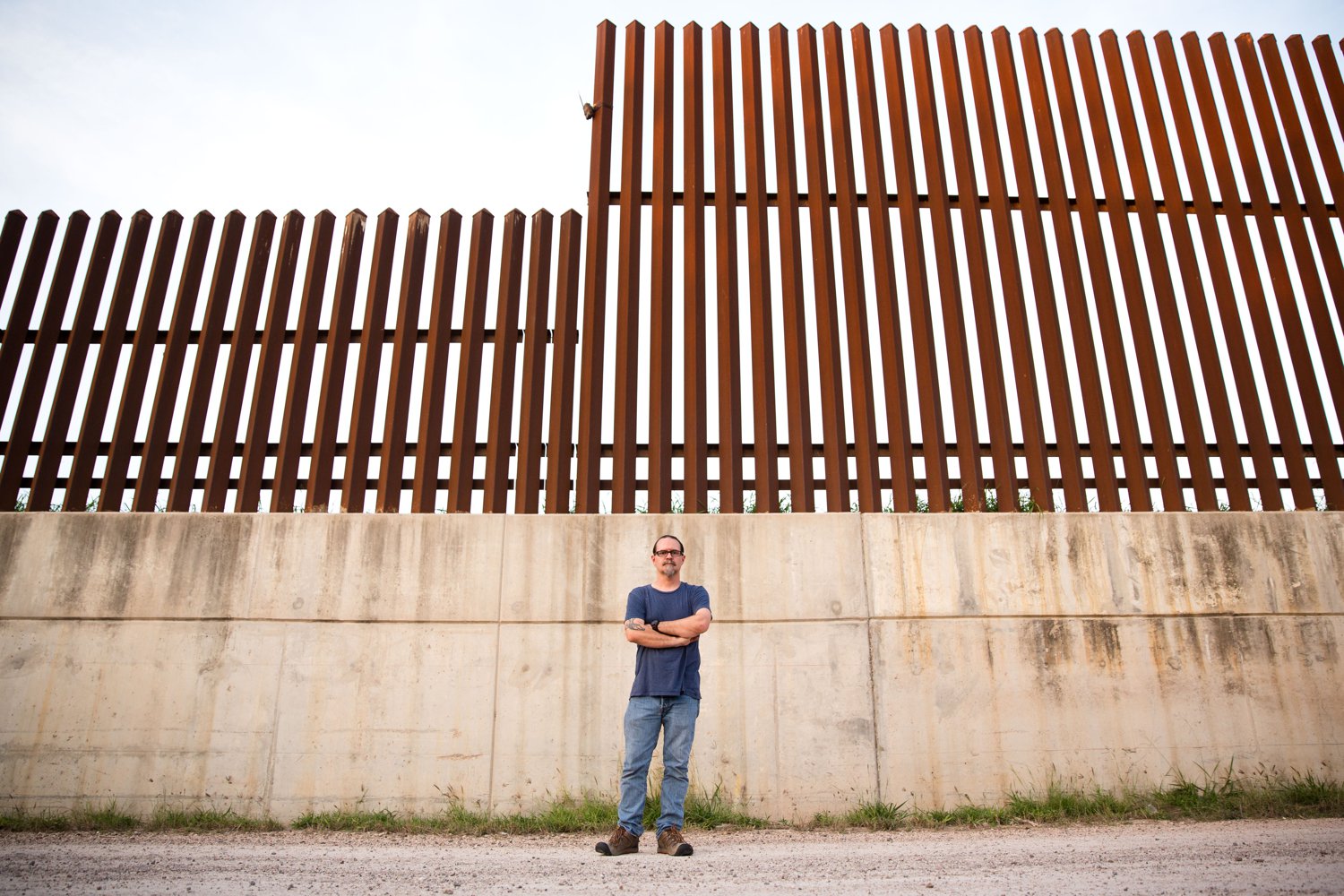 Scott Nicol, co-chair of the Sierra Club’s Borderlands Campaign, stands in front of a concrete levee topped by the border fence in Hidalgo County. Environmentalists, along with the U.S. Fish and Wildlife Service, say the barrier endangers wildlife because animals can't reach dry land during floods. Image by Callie Richmond. United States, 2017. Scott Nicol, co-chair of the Sierra Club’s Borderlands Campaign, stands in front of a concrete levee topped by the border fence in Hidalgo County. Environmentalists, along with the U.S. Fish and Wildlife Service, say the barrier endangers wildlife because animals can't reach dry land during floods. Image by Callie Richmond. United States, 2017.